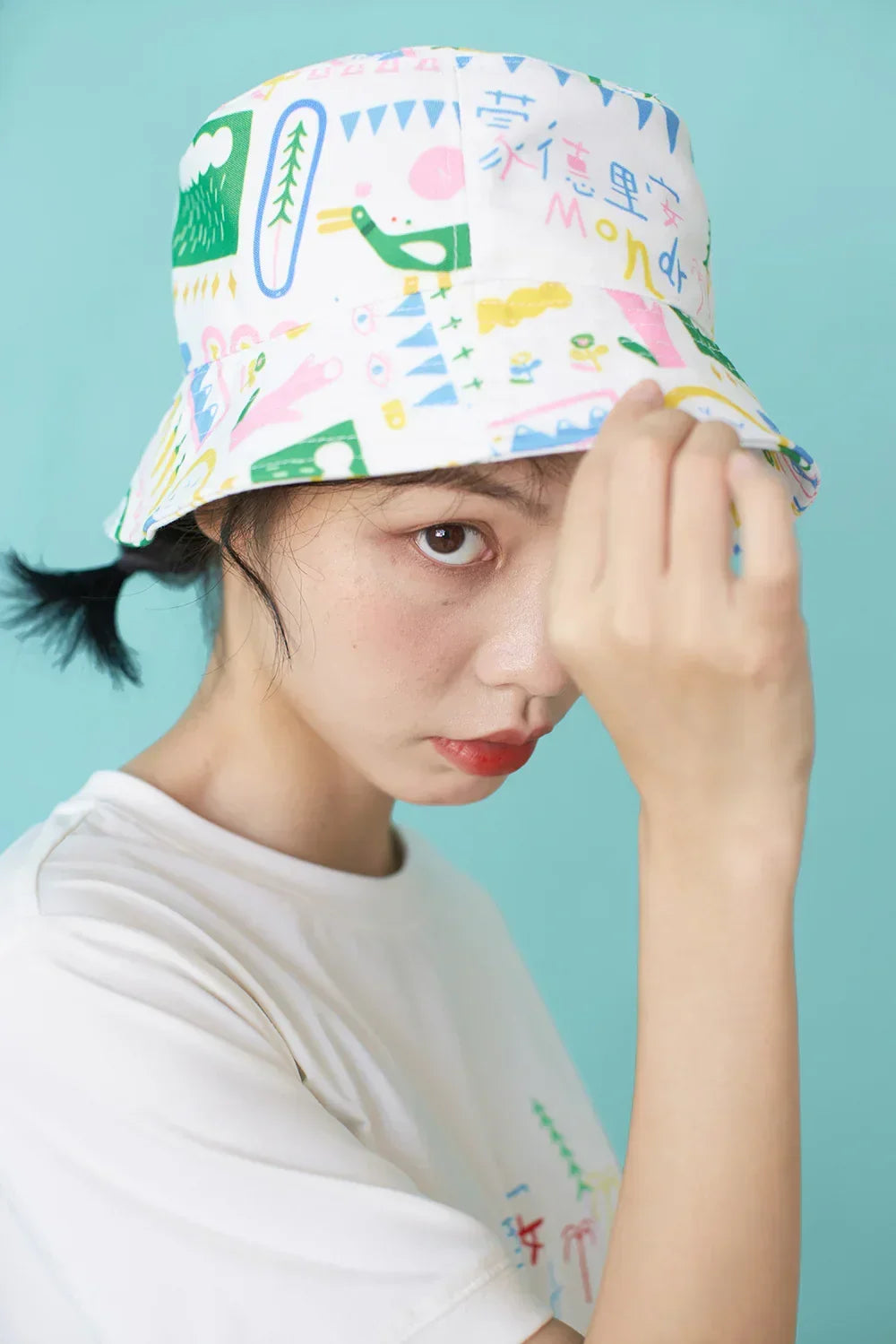 Woman in white graphic t-shirt and colorful patterned cotton bucket hat, relaxed fit