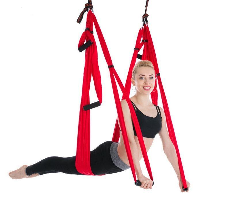 Woman in black crop top and leggings demonstrating red aerial yoga hammock