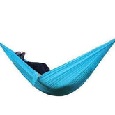 Person lounging in a light blue nylon hammock with relaxed fit and casual outdoor style
