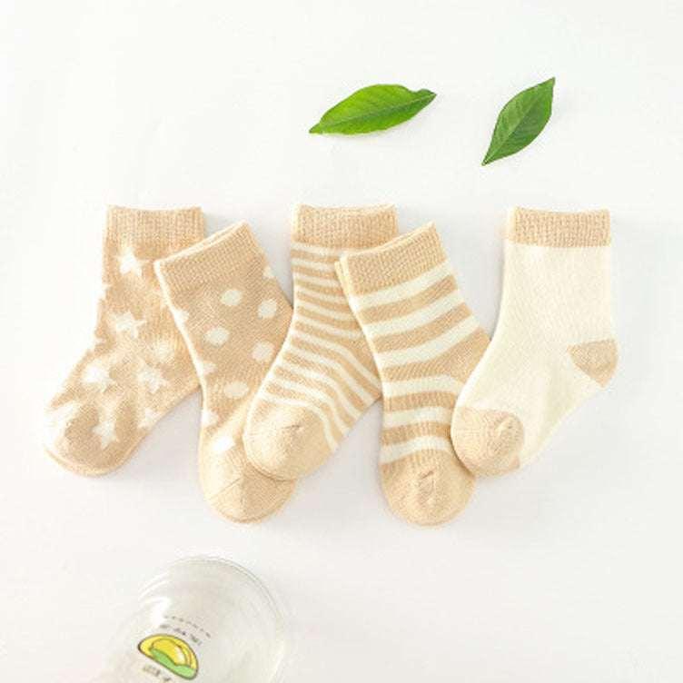 Set of four beige and cream cotton socks for babies, featuring star, dot, stripe, and solid patterns.