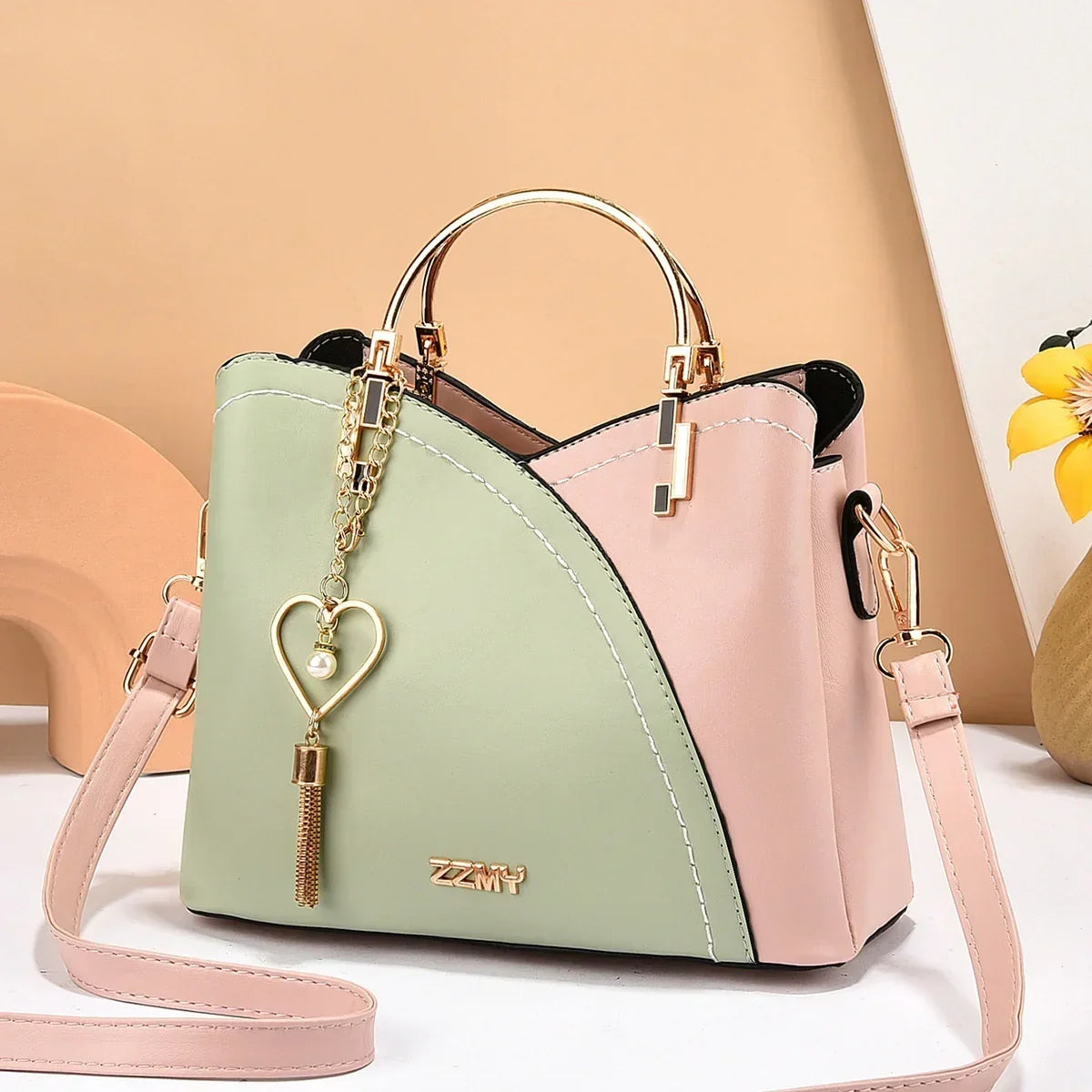Pastel green and pink color block handbag with gold metal handles, detachable strap, and heart charm