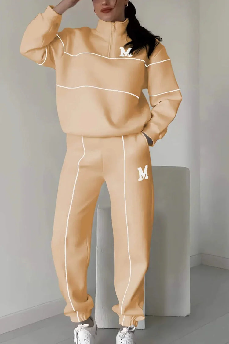 Woman wearing a beige oversized tracksuit with white piping and relaxed fit.