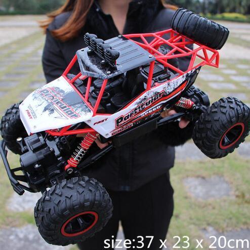 Woman in black jacket holding a large remote control off-road truck with rugged tires.