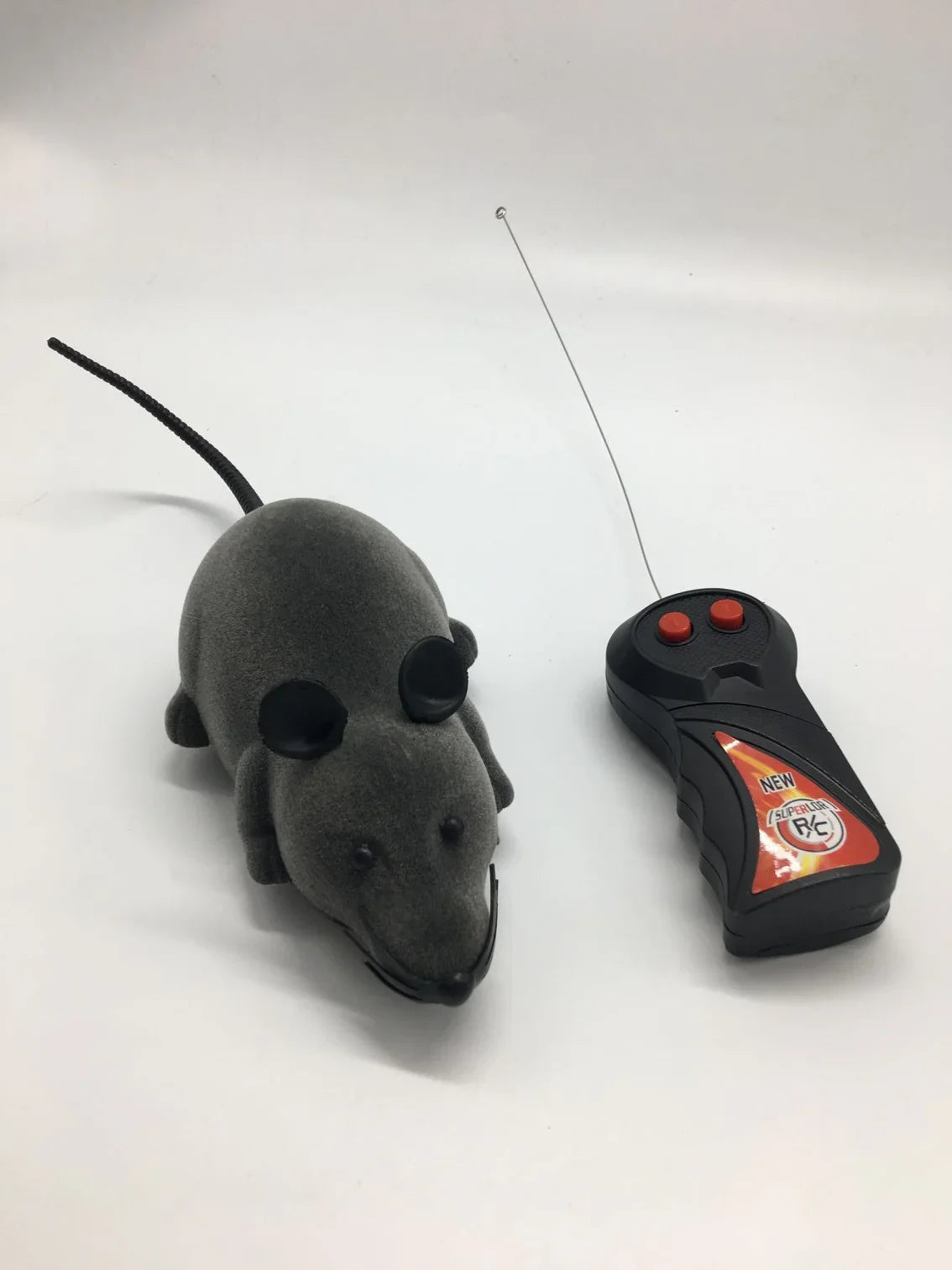 Grey remote control toy mouse with black ears and long tail on white background