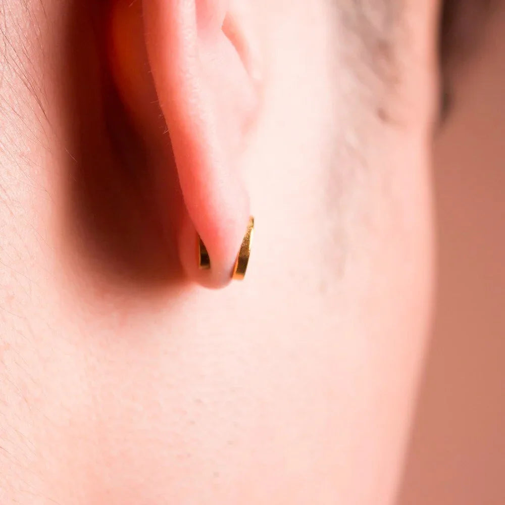 Close-up of a gold-toned hoop earring, minimalist style, worn on earlobe