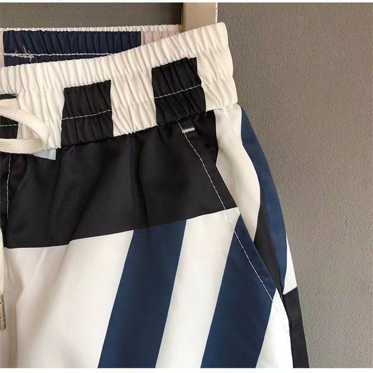 Close-up of elastic waist striped shorts in black, navy blue, and white polyester fabric