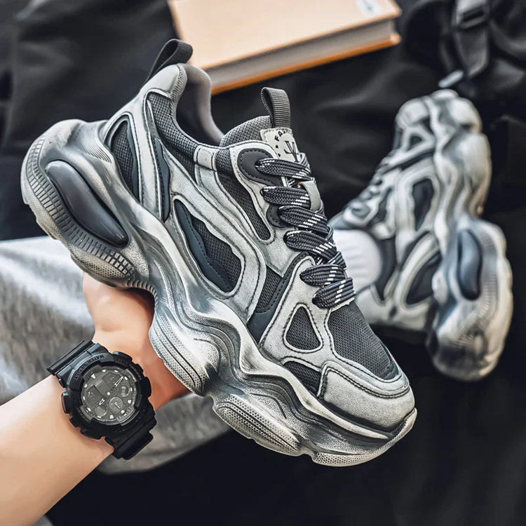Chunky grey and black mesh sneakers with futuristic design and thick textured sole.