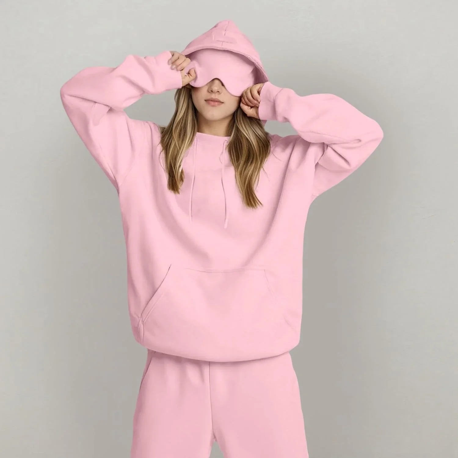 Woman in oversized light pink hoodie and matching sweatpants, soft cotton, relaxed fit