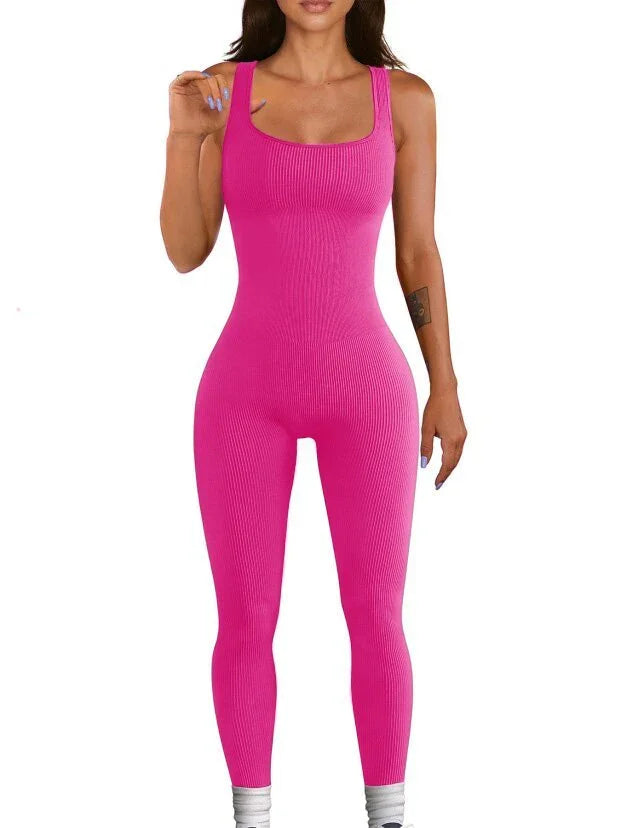 Woman wearing a fitted hot pink ribbed sleeveless jumpsuit, stretchy material, scoop neckline.