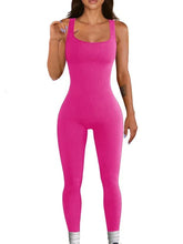 Woman wearing a fitted hot pink ribbed sleeveless jumpsuit, stretchy material, scoop neckline.