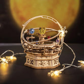 Wooden mechanical orrery model with colorful planets, surrounded by string lights