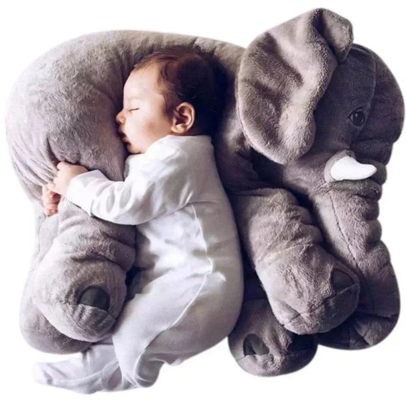 Baby in white cotton bodysuit cuddling large grey plush elephant pillow, cozy fit sleepwear