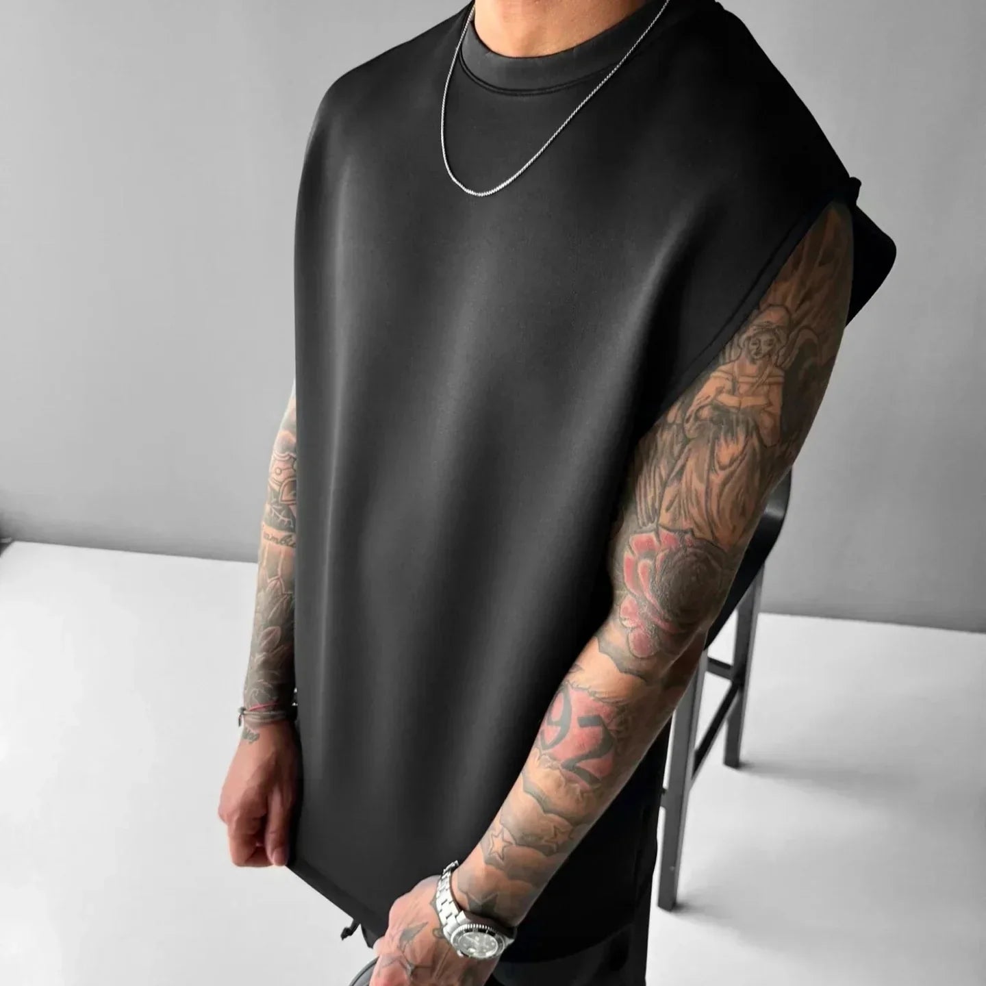 Man wearing a black oversized sleeveless shirt with relaxed fit and smooth texture