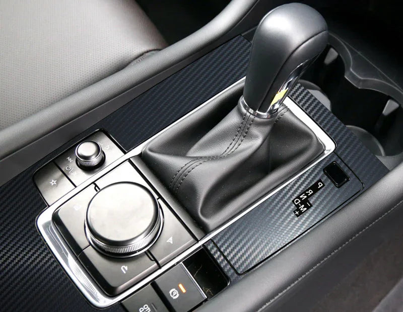 Close-up of modern car center console with black leather gear shift and carbon fiber trim