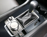 Close-up of modern car center console with black leather gear shift and carbon fiber trim
