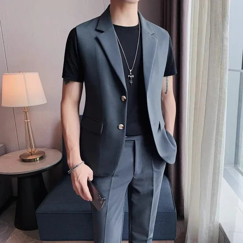 Men's gray sleeveless suit with notched lapel, paired with black t-shirt and slim-fit pants.