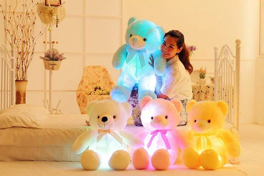 Woman posing with large plush teddy bears in glowing pastel colors on a bed, cozy bedroom setting