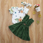 Baby girl floral print romper with ruffled short sleeves, green suspender skirt, and matching headband on wood background.