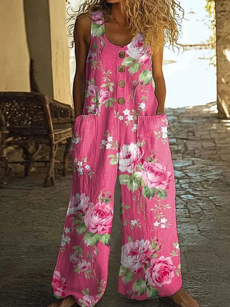 Woman wearing a loose pink floral sleeveless jumpsuit with button front and side pockets