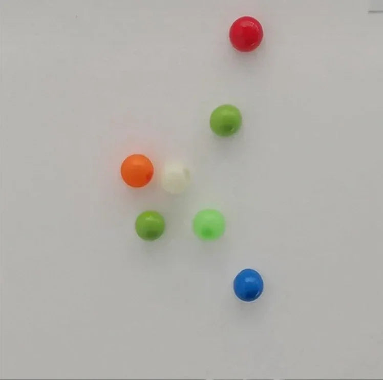 Assorted small round beads in red, green, blue, orange, and white on a white surface