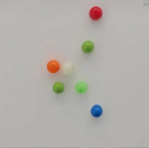 Assorted small round beads in red, green, blue, orange, and white on a white surface