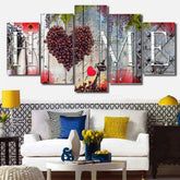 Modern living room with a white sofa, bold patterned pillows, yellow and blue accents, and a colorful wall art panel spelling HOME with coffee beans forming a heart.