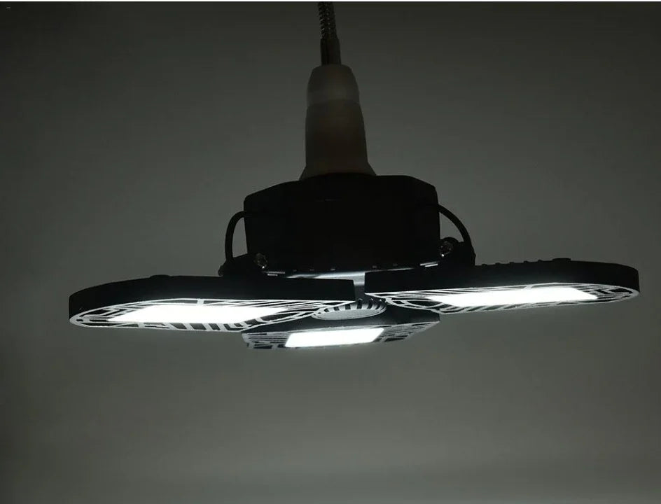 Modern LED ceiling light fixture with three adjustable black panels, emitting bright white light.