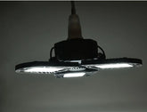 Modern LED ceiling light fixture with three adjustable black panels, emitting bright white light.
