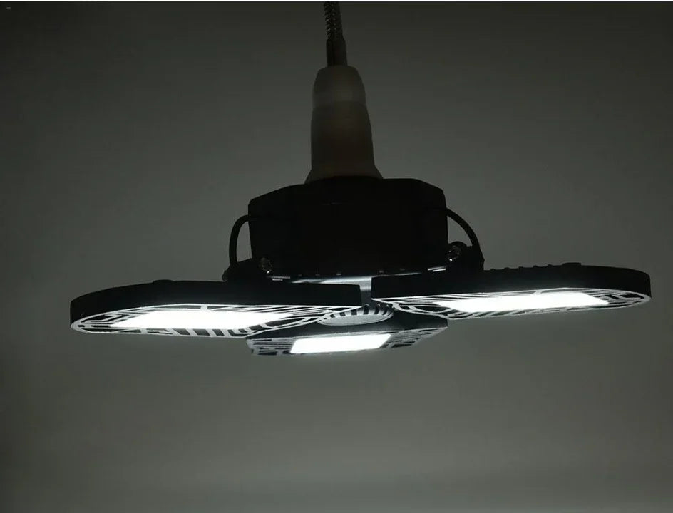 Modern LED ceiling light fixture with three adjustable black panels, emitting bright white light.