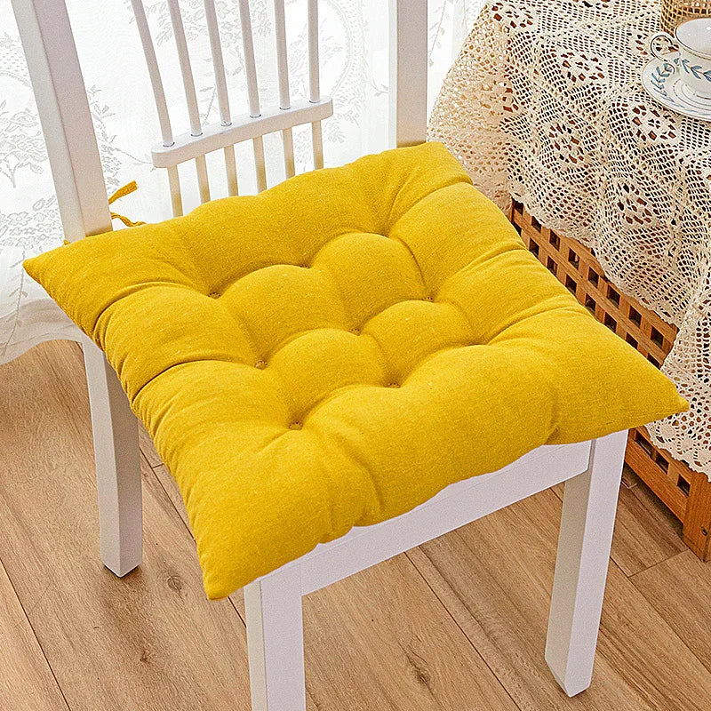 Bright yellow tufted cotton seat cushion on a white wooden chair in a cozy indoor setting