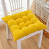 Bright yellow tufted cotton seat cushion on a white wooden chair in a cozy indoor setting