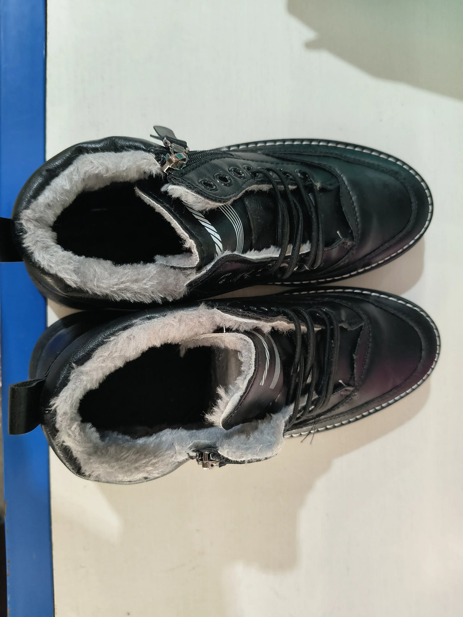 Black faux leather winter boots with white fur lining and lace-up front design