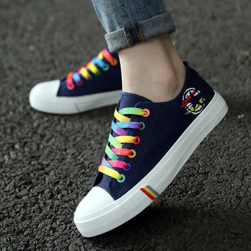 Navy canvas sneakers with rainbow laces, white rubber soles, and casual unisex fit.