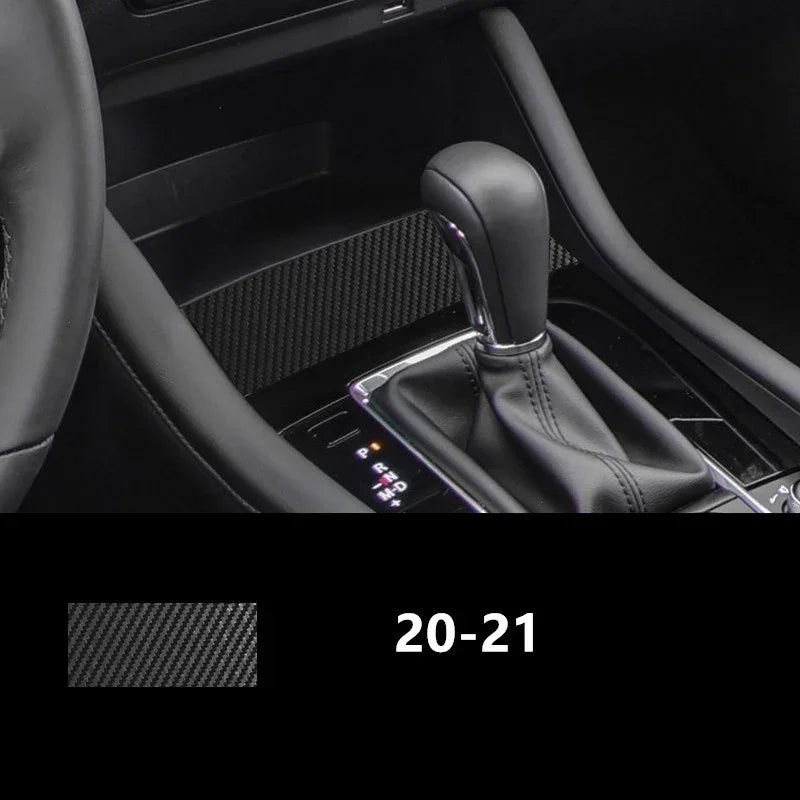 Black carbon fiber textured car interior trim near gear shift and steering wheel