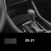 Black carbon fiber textured car interior trim near gear shift and steering wheel