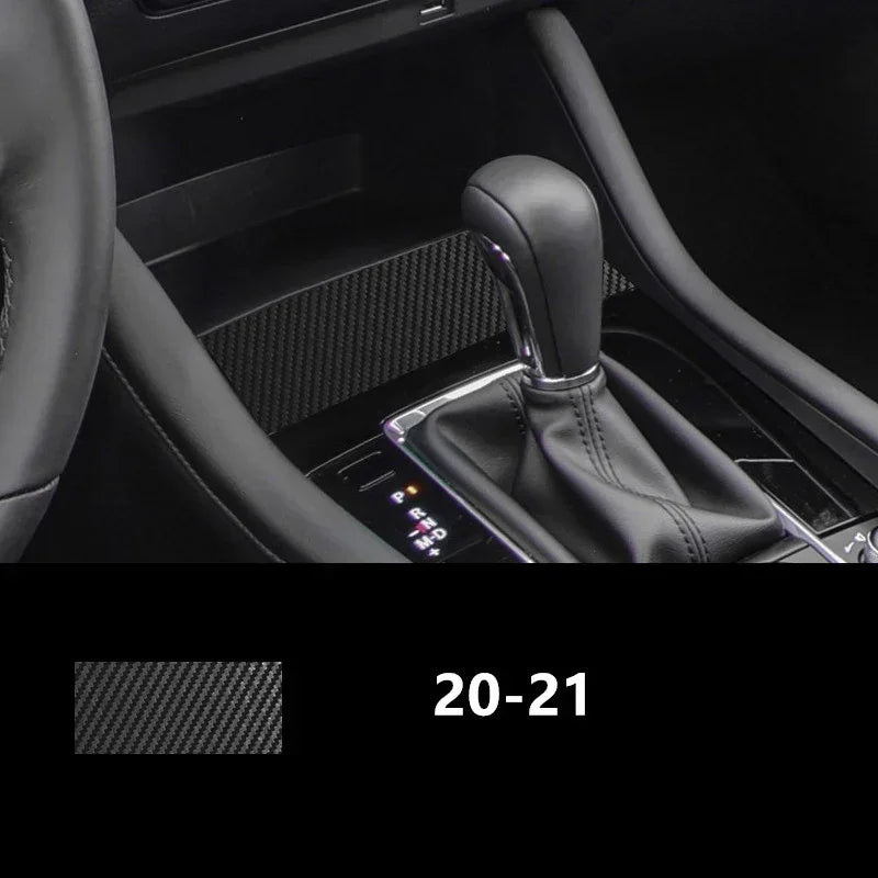 Black carbon fiber textured car interior trim near gear shift and steering wheel