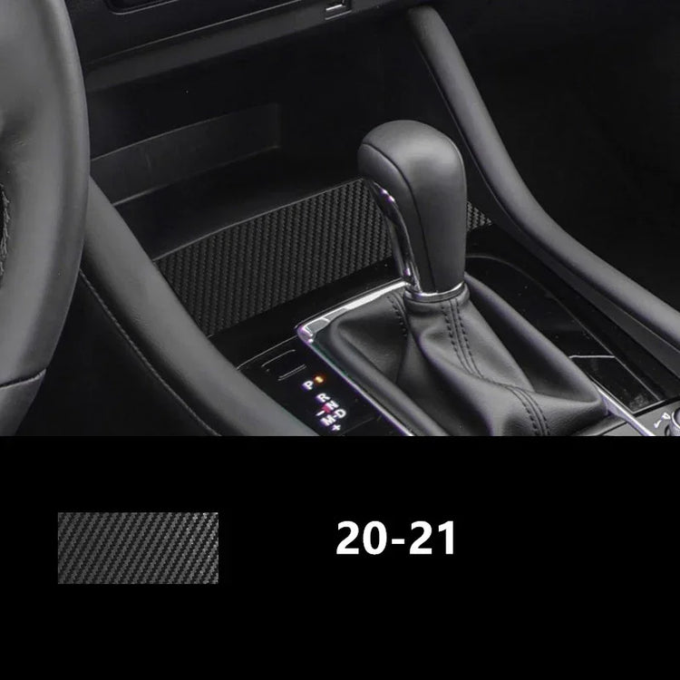 Black carbon fiber textured car interior trim near gear shift and steering wheel