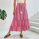 Woman wearing a pink boho maxi skirt with colorful chevron stripes, drawstring waist, and relaxed fit.