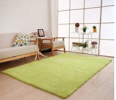 Modern living room with light green plush area rug, light wood flooring, neutral sofa and armchair.