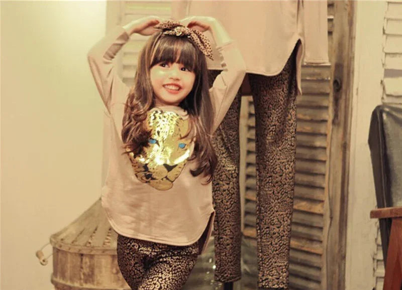 Girl in beige long-sleeve top with gold sequin tiger design and leopard print leggings