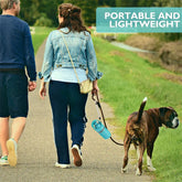 Woman wearing denim jacket, blue pants, and sneakers walking dog outdoors on a path