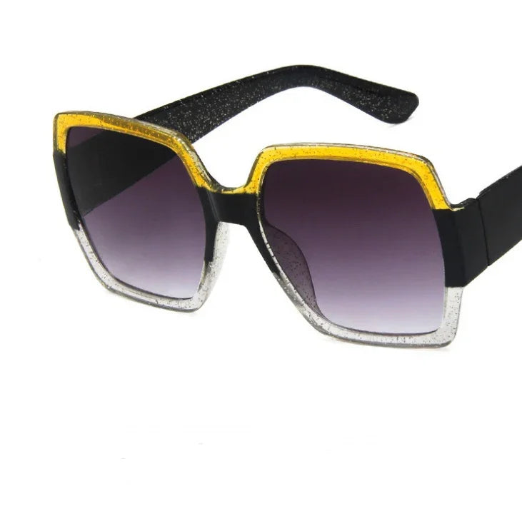Square oversized sunglasses with black arms, yellow and silver glitter frame, gradient lenses.