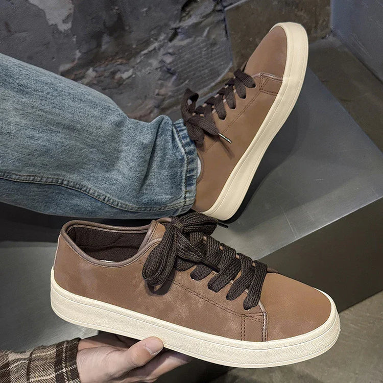 Brown low-top leather sneakers with black laces and white soles, casual streetwear style.
