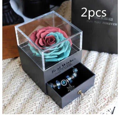 Gift box with artificial rose flower on top and drawer displaying blue beaded bracelets