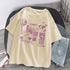 Oversized beige cotton t-shirt with purple graphic print, laid next to distressed denim shorts.