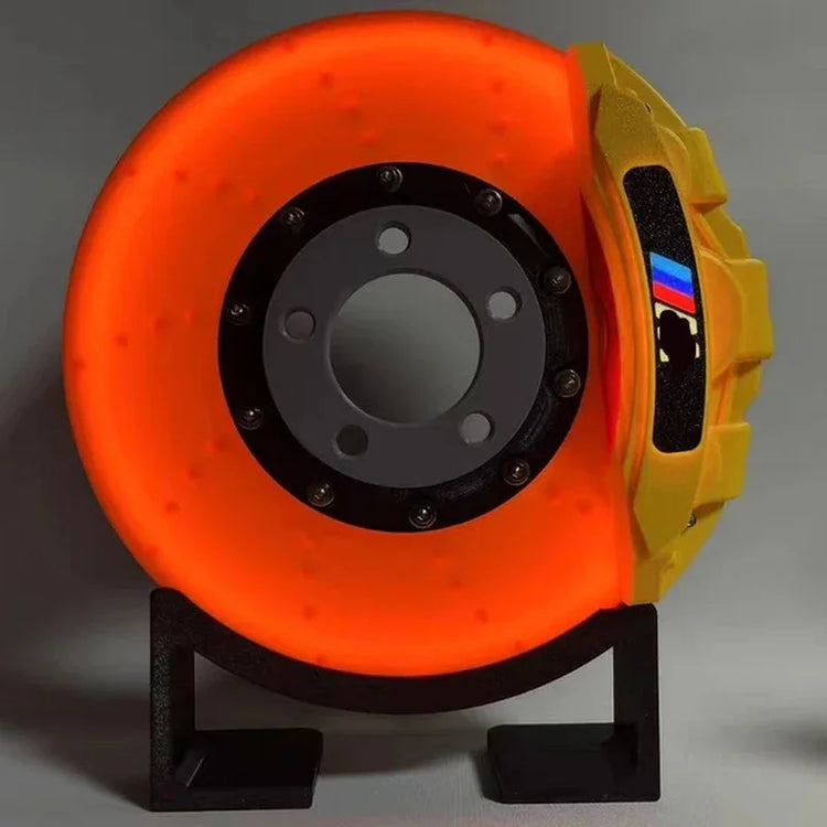 Glowing orange disc brake with yellow caliper and racing stripe, displayed on stand