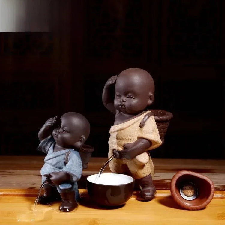 Ceramic figurines in blue and yellow robes with water feature, playful modern decor.