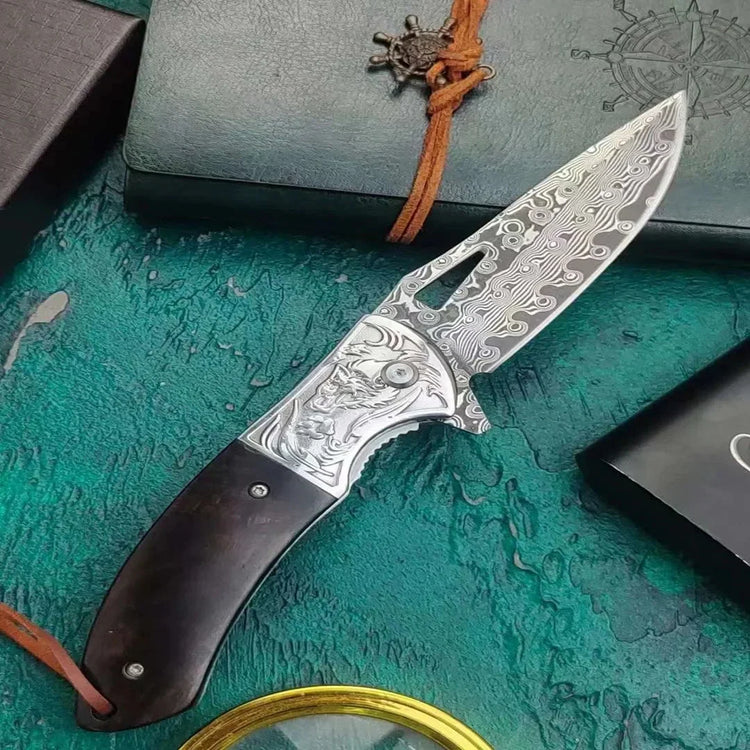 Damascus steel folding knife with engraved blade, dark wood handle, and ornate detail