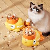 Long-haired cat beside yellow duck-shaped interactive pet food dispensers on wooden floor