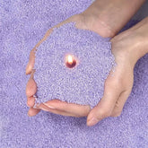 Hands holding purple foam beads with a small flame in the center